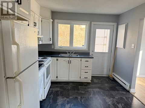 A kitchen with a white refrigerator and cabinets.