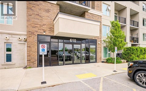 A black car is parked in a parking lot in front of a building with a sign that says REALTOR.