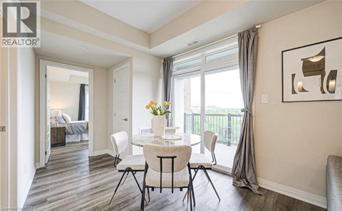 A dining room with a table set for two and a view of a bedroom through the open door.