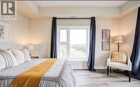 A bedroom with a large bed and a chair by the window.