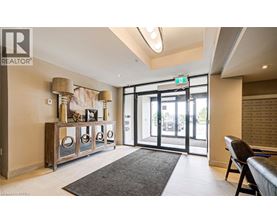 A well-lit room with a grey rug and a wooden cabinet with glass doors.