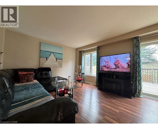 A living room with a black leather couch and a television.