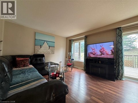 A living room with a black leather couch and a television.