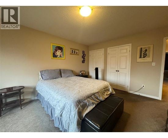 A bedroom with a bed, nightstand, and a painting on the wall.