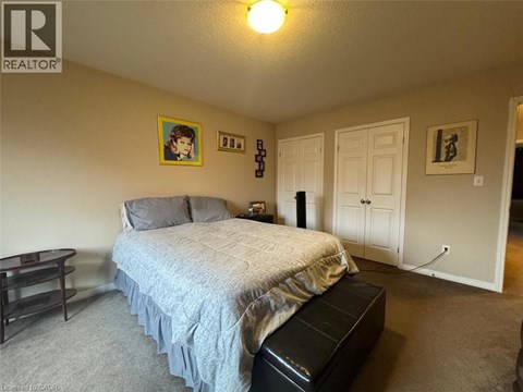 A bedroom with a bed, nightstand, and a painting on the wall.