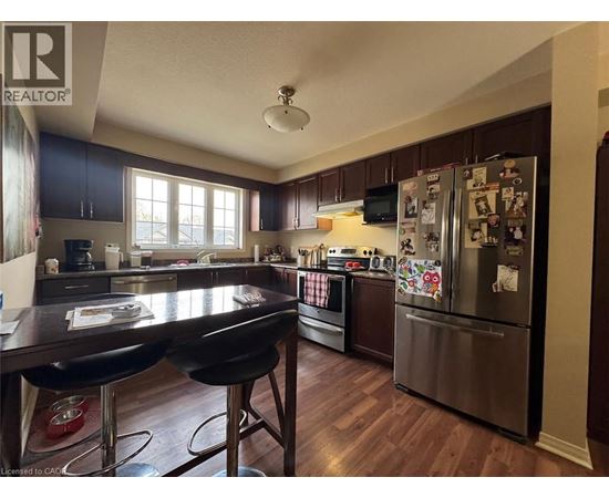 A kitchen with a table and chairs in the foreground and a refrigerator covered in magnets in the background.