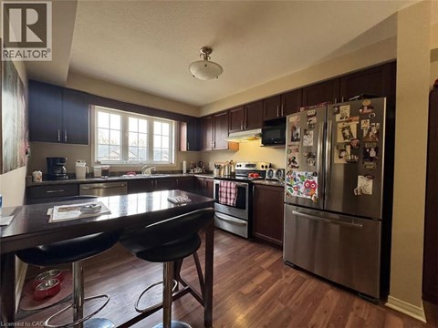 A kitchen with a table and chairs in the foreground and a refrigerator covered in magnets in the background.