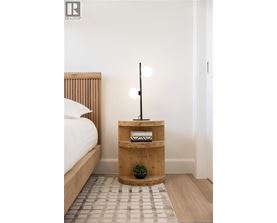 A bedroom with a bed, a wooden nightstand with a plant and a lamp.