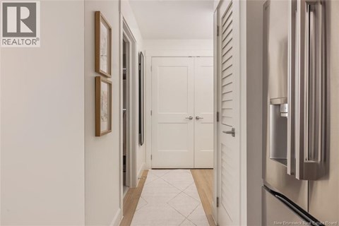 A hallway with a white door and a fridge on the side.