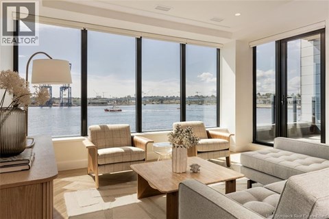 A living room with a view of the water and boats outside the large windows.
