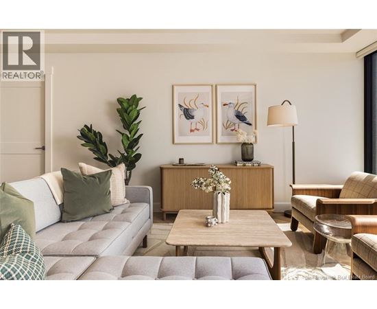A living room with a grey couch, a wooden table, and a painting on the wall.