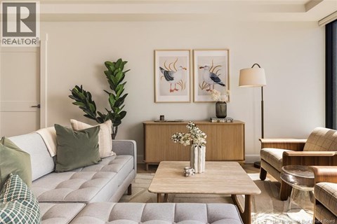 A living room with a grey couch, a wooden table, and a painting on the wall.