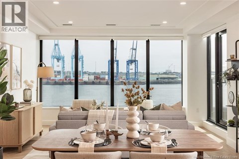 A well-lit dining room with a view of the water and cranes outside the window.