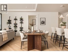 A dining room with a table set for two and a sofa with a blanket on it.