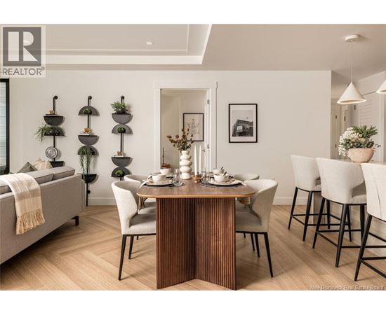 A dining room with a table set for two and a sofa with a blanket on it.