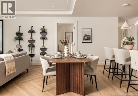 A dining room with a table set for two and a sofa with a blanket on it.