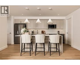 A modern kitchen with white chairs and a wooden floor.