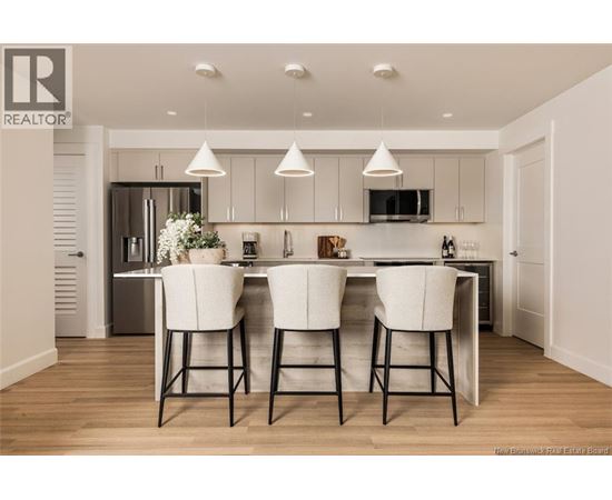 A modern kitchen with white chairs and a wooden floor.