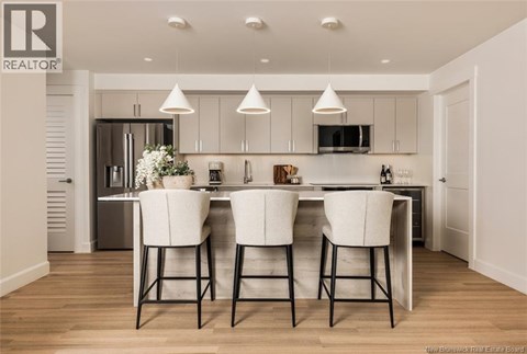 A modern kitchen with white chairs and a wooden floor.