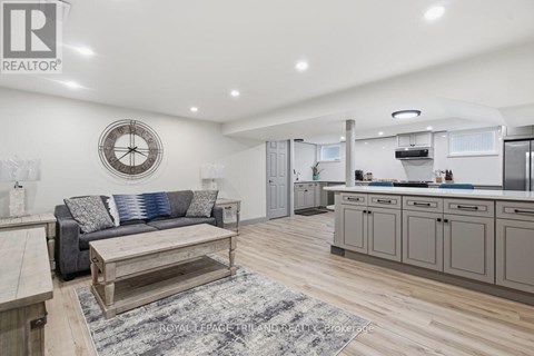 A well-lit kitchen and living room with a clock on the wall.