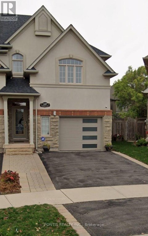 A house with a garage and a driveway in front of it.