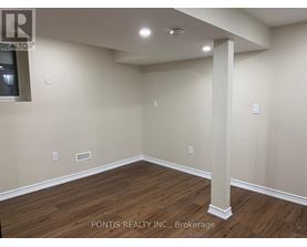 A room with wooden flooring and a white pillar in the middle.