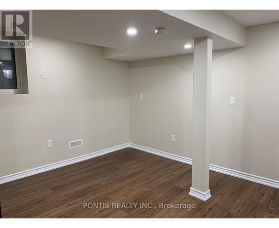 A room with wooden flooring and a white pillar in the middle.