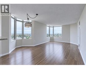 A large empty room with wooden floors and a view of the city through the windows.
