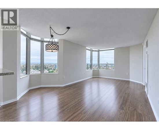A large empty room with wooden floors and a view of the city through the windows.