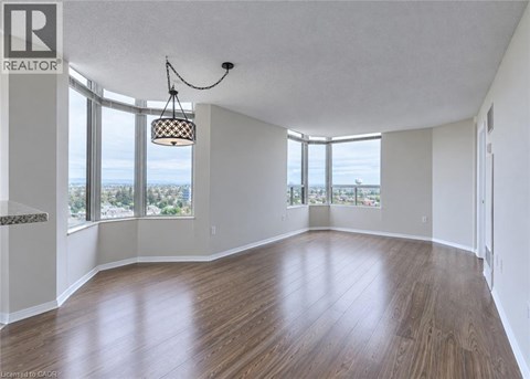 A large empty room with wooden floors and a view of the city through the windows.