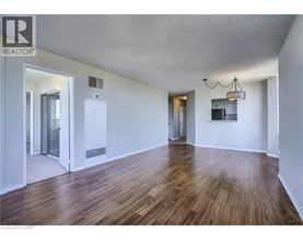A room with wooden floors and white walls, with a chandelier hanging from the ceiling.
