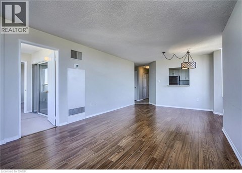 A room with wooden floors and white walls, with a chandelier hanging from the ceiling.