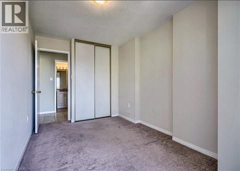 A bedroom with a carpeted floor and a sliding door.