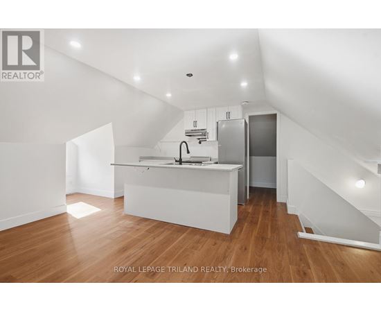 A white kitchen with wooden floors and a staircase.
