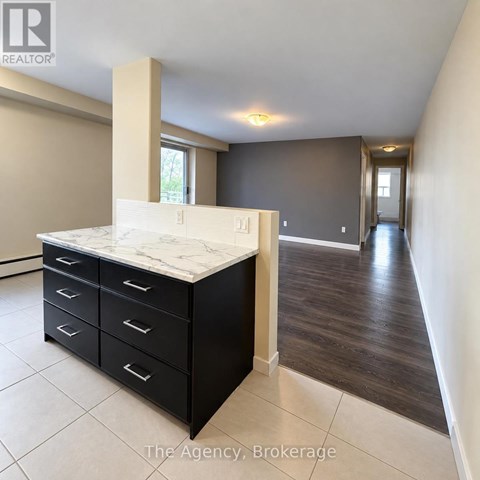 A room with a marble top counter and black drawers.