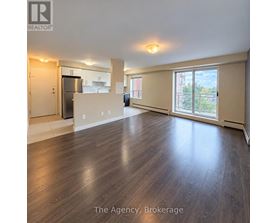 A spacious living room with wood flooring and a view of the city.