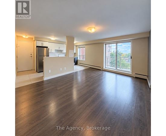 A spacious living room with wood flooring and a view of the city.