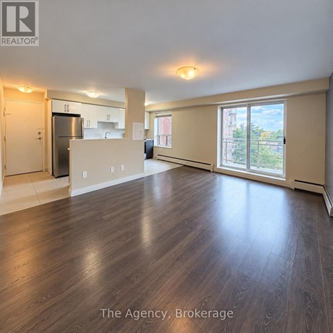 A spacious living room with wood flooring and a view of the city.