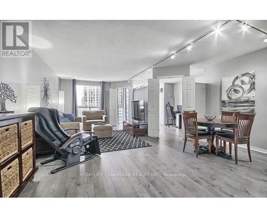 A well-lit living room with a dining area and a kitchen in the background.