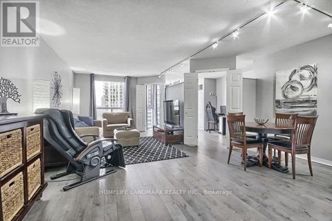 A well-lit living room with a dining area and a kitchen in the background.