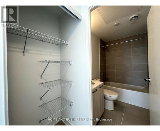 A bathroom with a walk-in shower and a pantry with shelves.