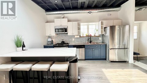 A modern kitchen with a bar stool and a plant on the counter.