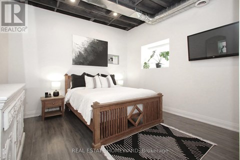 A bedroom with a large bed and a TV mounted on the wall.