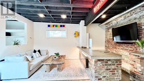 A living room with a white couch and a brick wall.