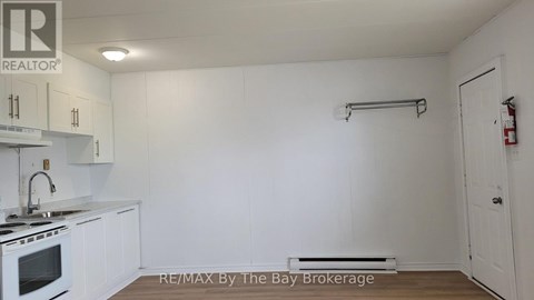 A white kitchen with a stove and a white door.