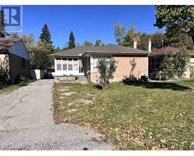 A house with a driveway and a tree in front of it.