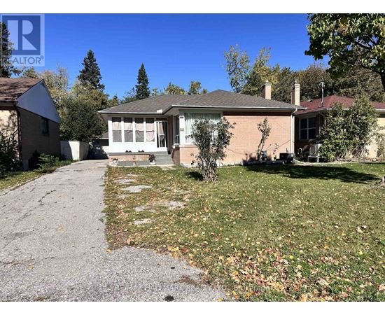 A house with a driveway and a tree in front of it.