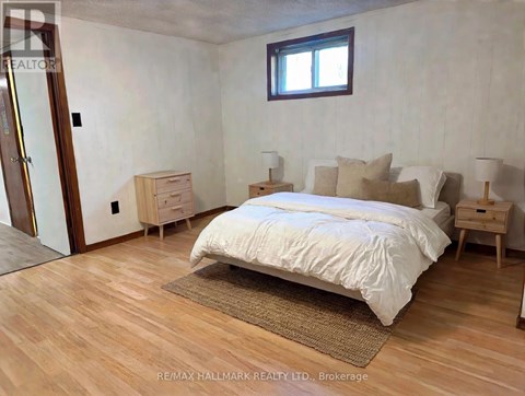 A bedroom with a bed, nightstands, and a window.