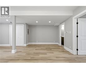 A realtor logo is on a wall in a room with wood flooring.