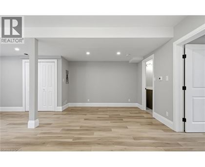 A realtor logo is on a wall in a room with wood flooring.